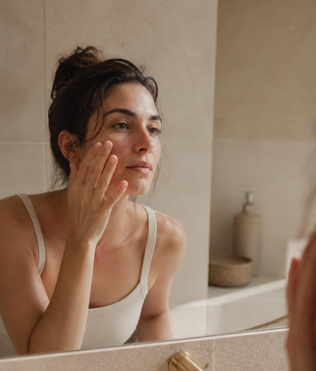 Woman with bare skin at a bathroom basin in morning light